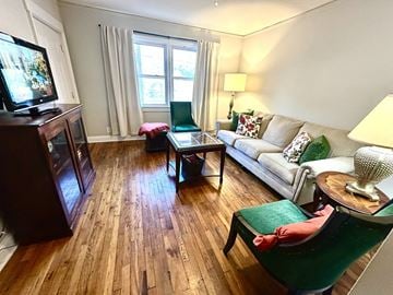 Raleigh triplex for rent - A living room with a green chair and a white couch.