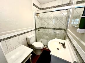 Raleigh triplex for rent - A white toilet sits in a bathroom with a marble tile shower.