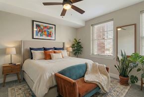 Fayetteville townhouse for rent - A bedroom with a bed, a ceiling fan, and a potted plant.