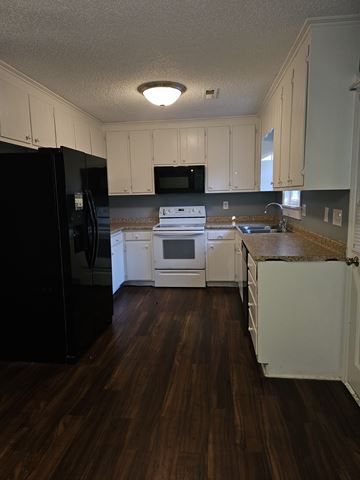 Cary triplex for rent - A kitchen with black appliances and white cabinets.