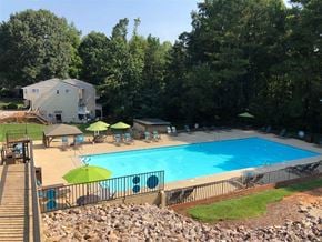 Raleigh townhouse for rent - A large swimming pool surrounded by a black fence and green umbrellas.