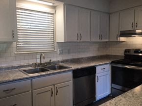 Raleigh townhouse for rent - A kitchen with white cabinets and a black stove top oven.