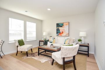 Fayetteville townhouse for rent - A living room with a white sofa, a chair with a green pillow, and a painting on the wall.