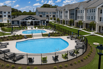 Fayetteville townhouse for rent - A large swimming pool surrounded by lounge chairs and a fence.