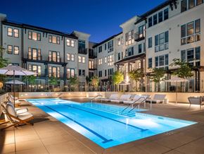 Menlo Park apartment for rent - A swimming pool surrounded by lounge chairs and umbrellas in front of apartment buildings.