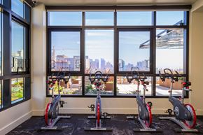 San Francisco apartment for rent - A gym with exercise bikes and a view of the city outside the window.