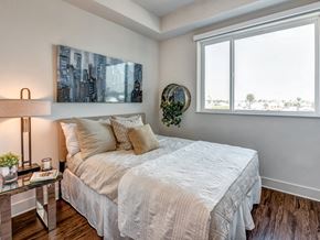 Los Angeles apartment for rent - A bedroom with a large bed and a cityscape painting on the wall.