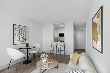 Toronto apartment for rent - A modern living room with a white sofa, a round table with chairs, and a painting on the wall.