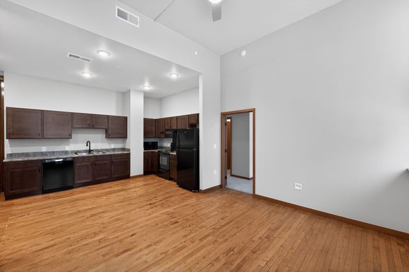 Sioux City apartment for rent - A kitchen with dark wood cabinets and a black fridge.