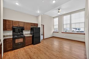 Sioux City apartment for rent - A kitchen with wooden floors and a black refrigerator.