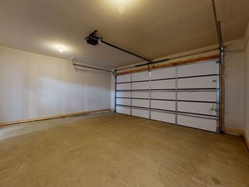 A large empty room with a white door and a black pipe running along the ceiling.