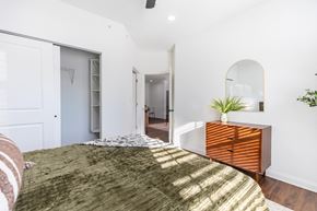 West Des Moines apartment for rent - A bedroom with a bed in the foreground and a dresser with a mirror above it.
