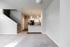 Des Moines apartment for rent - A spacious, empty room with a staircase on the left and a kitchen area in the background.