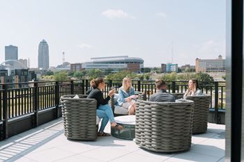 Four people are sitting on a rooftop terrace.