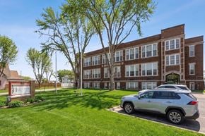 Sioux City apartment for rent - A silver car is parked in front of a brick building with a sign that reads "Heartland".