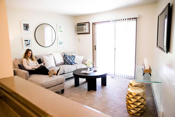 Des Moines apartment for rent - a woman sitting on a couch reading a book in a living room at Rosemont Place Apartments, Iowa, 50320