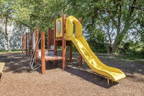 Newton apartment for rent - a playground with a slide and chairs in a park at Hunters Run Apartments, Newton, IA