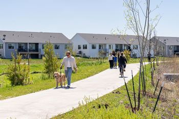 A man walking his dog down a sidewalk in front of houses