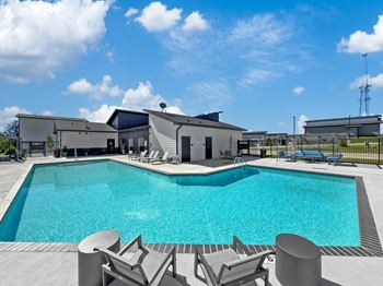 A swimming pool with chairs and a building in the background
