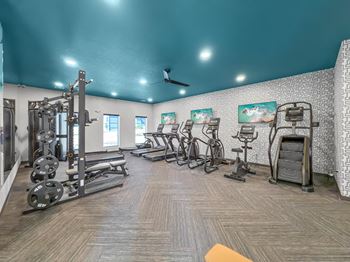 A gym with cardio equipment and weights on the floor