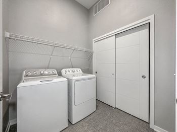 A laundry room with a washer and dryer and a white closet.