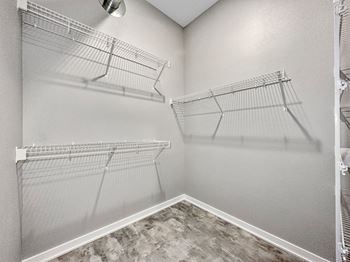 A walk-in closet with shelving and a fan.