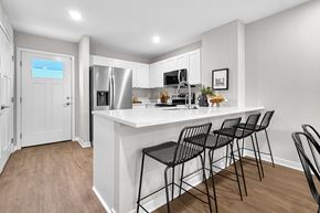 La Vista apartment for rent - A kitchen with white cabinets and a white island with four black chairs.