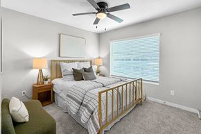 La Vista apartment for rent - A bedroom with a bed, a green chair, and a ceiling fan.