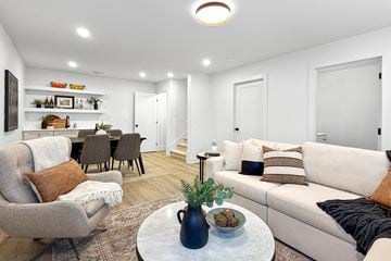 West Des Moines townhouse for rent - A living room with a grey armchair, a white sofa, and a coffee table with a vase of flowers on it.