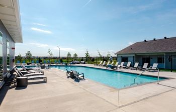A pool area with sun loungers and a building in the background.