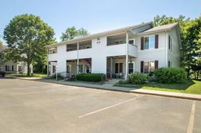 Newton apartment for rent - A white two-story building with a parking lot in front at Hunters Run Apartments, Newton