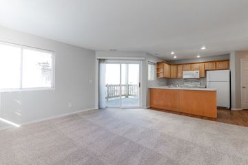 Polk City apartment for rent - A spacious living room with a carpeted floor and a kitchen area with wooden cabinets and a white refrigerator.