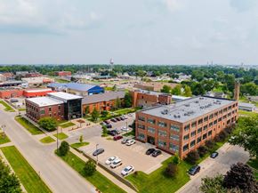 Grinnell apartment for rent - A large building complex with a parking lot in front at Spaulding Lofts Apartments, Grinnell, IA