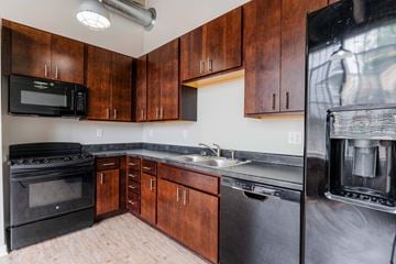 Grinnell apartment for rent - A kitchen with wooden cabinets and black appliances.