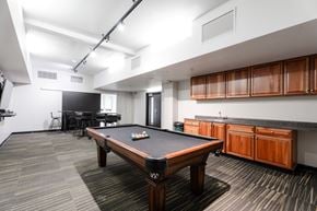 Des Moines apartment for rent - A pool table is in the middle of a room with a black chair and a TV.
