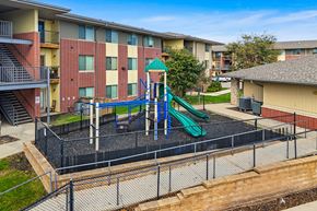 Des Moines apartment for rent - A playground with a green slide and a black fence.