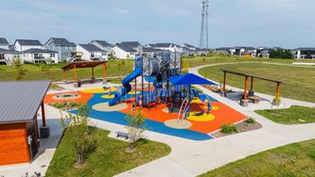 An aerial view of a colorful playground with houses in the background
