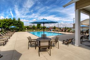 Waukee apartment for rent - a swimming pool with a table and chairs under an umbrella at The Winhall of Williams Pointe Apartments, IOWA