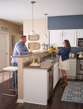 Waukee apartment for rent - a man and a woman standing at a kitchen island at The Winhall of Williams Pointe Apartments, Waukee