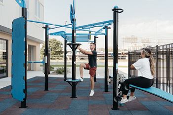 A man and a woman are exercising at a park.