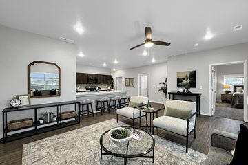 Waukee apartment for rent - A living room with a ceiling fan and a dining table with chairs.