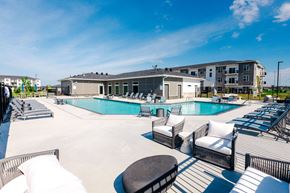 Waukee apartment for rent - A large outdoor swimming pool area with lounge chairs and a building in the background.at Converge NW, Waukee, IA 50263  