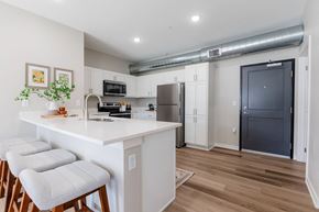 Waukee apartment for rent - A kitchen with white cabinets and a white island with three stools at Converge NW, Waukee, 50263