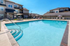 Clive apartment for rent - A swimming pool surrounded by a wooden deck and a fence. at Stonegate Crossing Apartments, IOWA