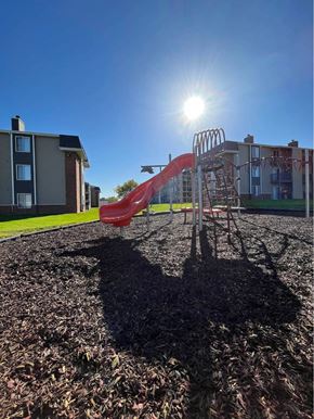 Sioux Falls apartment for rent - A playground with a red slide and a person's shadow on the ground at Penbrooke Place Apartments, Sioux Falls, SD, 57106