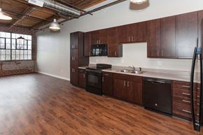 Grinnell apartment for rent - A kitchen with wooden floors and dark brown cabinets at Spaulding Lofts Apartments, Grinnell, IA