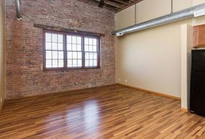 Des Moines apartment for rent - A room with wooden floors and a brick wall with a window.at Riverpoint Lofts, Des Moines, 50309