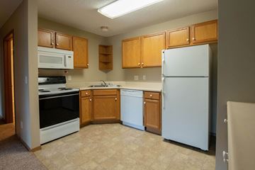 Ankeny apartment for rent - A kitchen with a white refrigerator, white oven, and brown cabinets.
