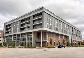 Des Moines apartment for rent - A large, modern building with a parking lot in front.at City Square Lofts, Iowa, 50309