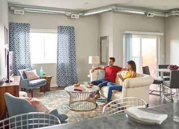 Des Moines apartment for rent - A man and woman are sitting on a couch in a living room with a coffee table in front of them.
